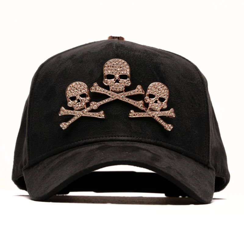 Gorra suede negra con tres calaveras y huesos cruzados en pedrería oro rosa.