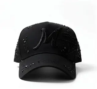 Gorra negra con letra M en pedrería y detalles brillantes.