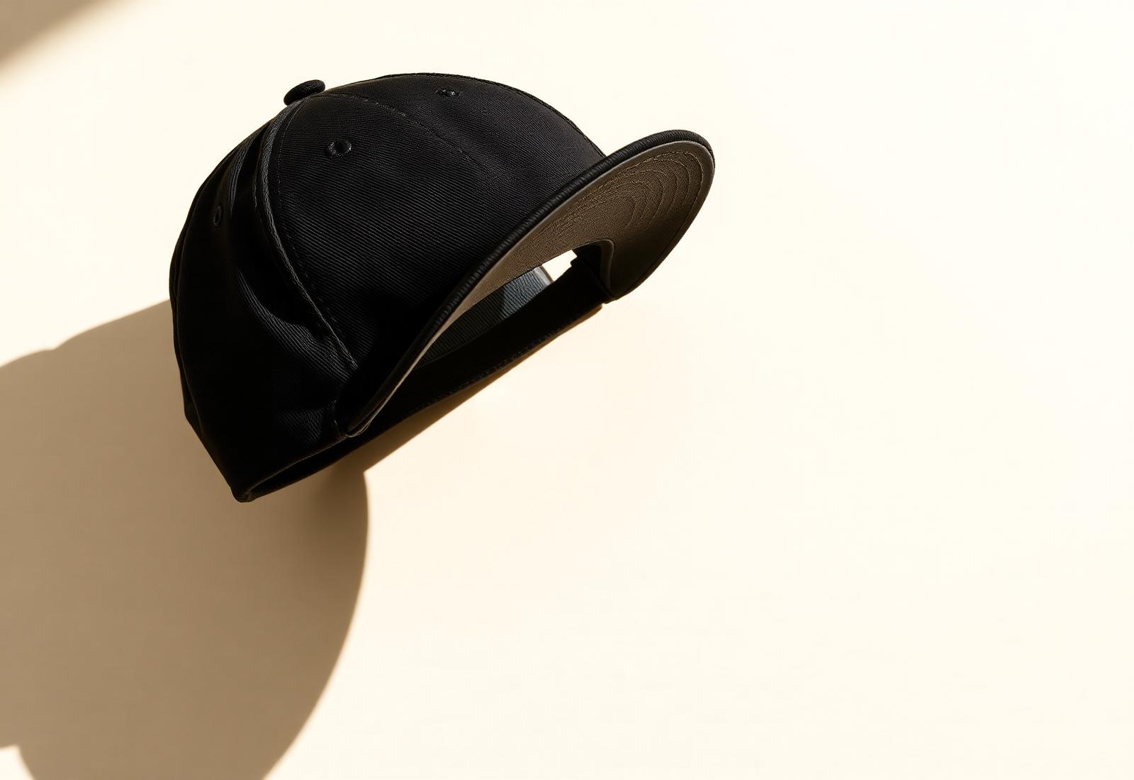 Gorra premium negra sobre fondo crema con sombra marcada.